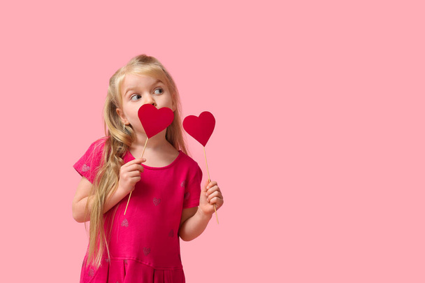 Nettes kleines Mädchen mit roten Papierherzen auf rosa Hintergrund. Valentinstag-Feier - Foto, Bild