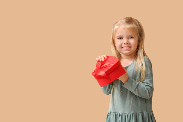 Słodka dziewczynka z pudełkiem na beżowym tle. Święto Walentynek - Zdjęcie, obraz