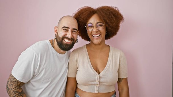 Glückliches, selbstbewusstes gemischtrassiges Paar in lässiger Kleidung, liebevoll zusammenstehend mit strahlendem Lächeln, das Freude und positiven Lebensstil projiziert, isoliert über einer schönen rosa Hintergrundwand. - Foto, Bild