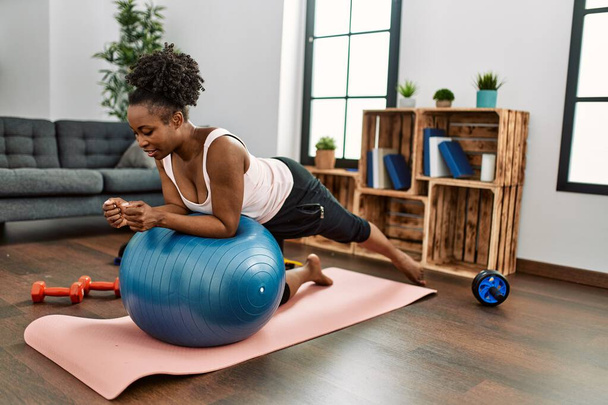 Afroamerikanerin trainiert Bauchmuskeltraining mit Fitnessball zu Hause - Foto, Bild