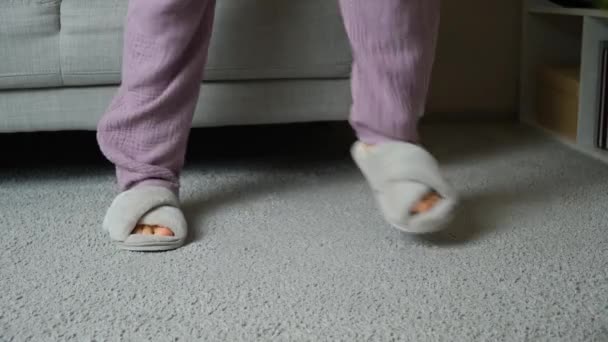 Felices zapatillas de felpa casa, mujer bailando y saltando en casa en la alfombra. Cómodos y modernos zapatos para el hogar - Metraje, vídeo
