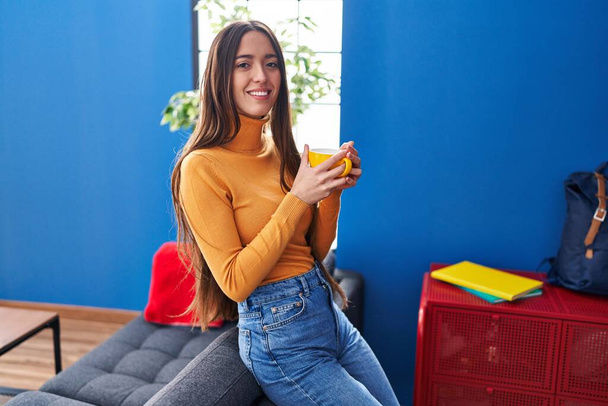 Joven mujer hispana hermosa bebiendo café de pie en casa - Foto, imagen