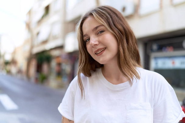 Junge Kaukasierin lächelt selbstbewusst auf der Straße - Foto, Bild
