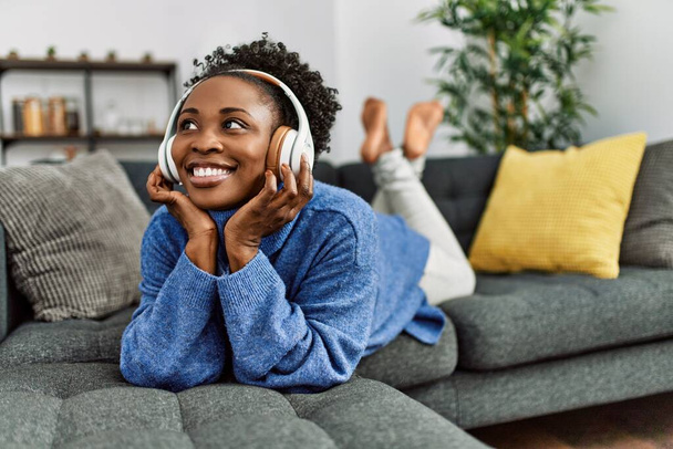 Afrikai amerikai nő zenét hallgat otthon a kanapén - Fotó, kép