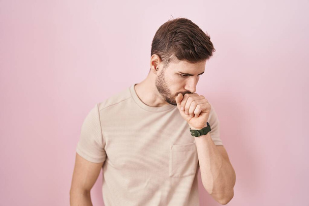 Hombre hispano con barba de pie sobre fondo rosado sintiéndose mal y tosiendo como síntoma de resfriado o bronquitis. concepto de atención sanitaria.  - Foto, imagen