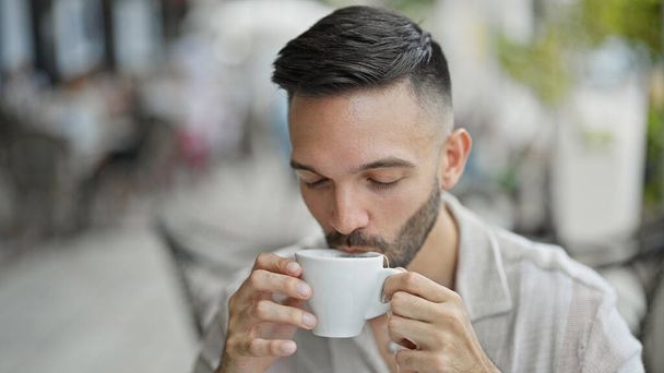 コーヒーショップテラスで紅茶を飲む若いヒスパニックの男 - 写真・画像