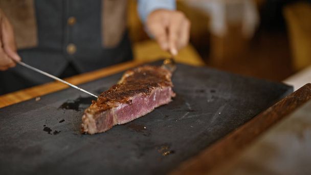 Νεαρός που σκαλίζει κρέας στο εστιατόριο - Φωτογραφία, εικόνα