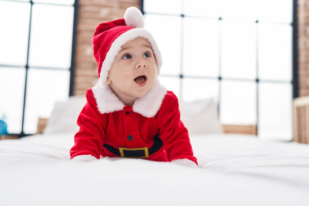Adorabile bambino caucasico che indossa il costume di Natale sdraiato sul letto in camera da letto - Foto, immagini
