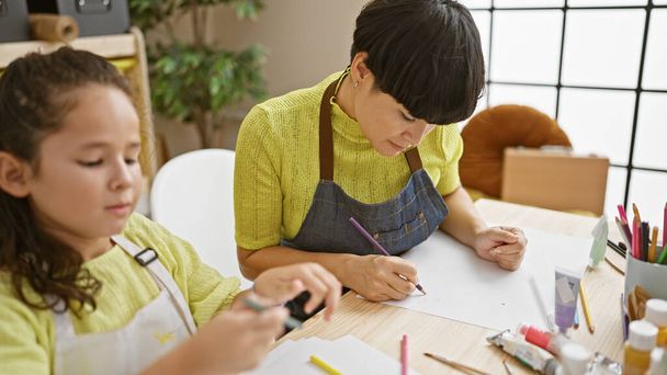 Artiste enseignant et étudiant dessinant sur toile ensemble dans une leçon d'atelier d'art, se concentrant et apprenant créativement à l'intérieur - Photo, image
