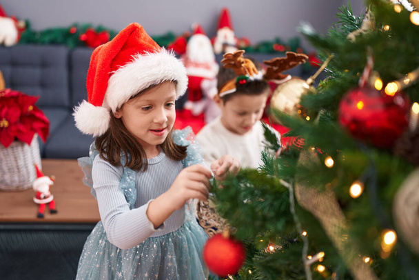 Imádnivaló fiú és lány díszítő karácsonyfa otthon - Fotó, kép