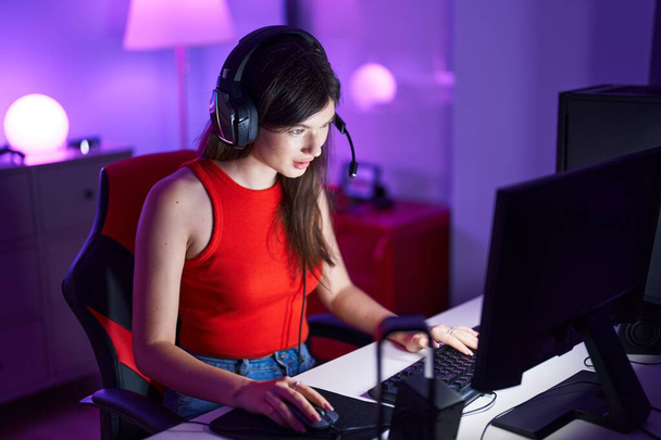 Joven mujer caucásica streamer jugando videojuego utilizando la computadora en la sala de juegos - Foto, imagen
