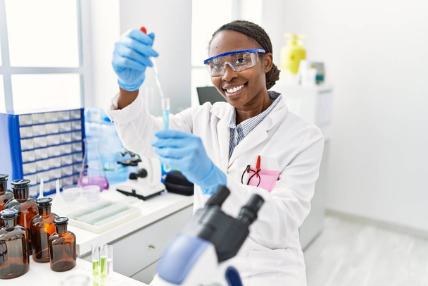 アフリカ系アメリカ人女性科学者が実験室で試験管に液体を注ぐ - 写真・画像