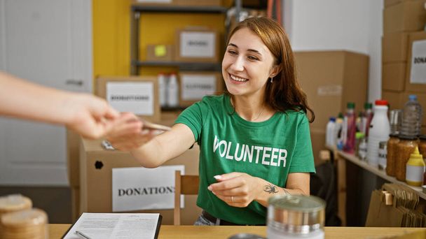Mujer joven voluntaria recibiendo dólares sonriendo en el centro de caridad - Foto, imagen