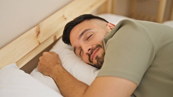 Jeune homme hispanique couché sur le lit dormant dans la chambre - Photo, image
