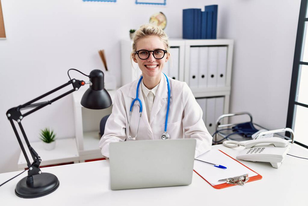 Fiatal szőke nő orvos használó laptop dolgozik a klinikán - Fotó, kép
