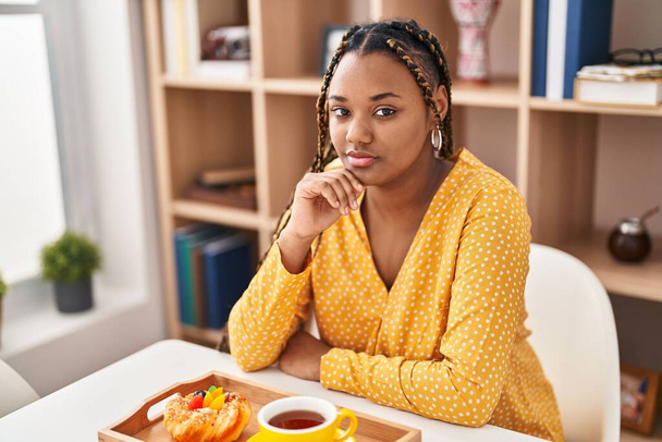 Afrikkalainen amerikkalainen nainen syö aamiaista istuu pöydällä kotona - Valokuva, kuva