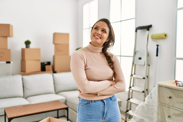 Young beautiful hispanic woman smiling confident standing with arms crossed gesture at new home - Foto, Imagen