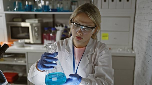 A young woman scientist conducting research in a laboratory while holding beakers - Photo, Image