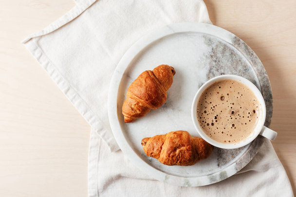 Cup of coffee with croissants on marble tray. - Foto, afbeelding