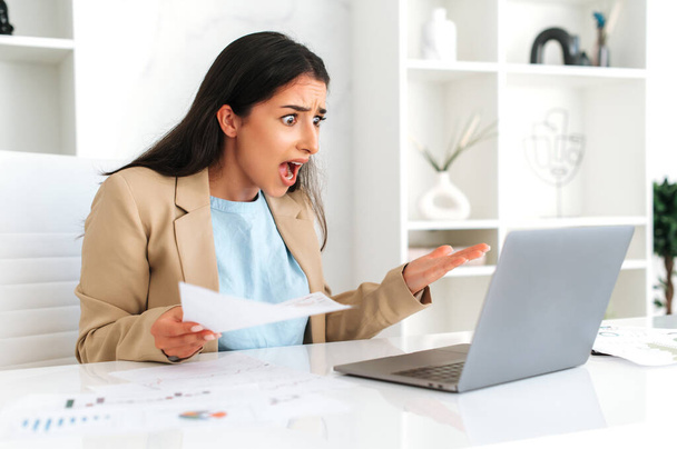 Podenerwowana sfrustrowana arabska lub indyjska kobieta biznesu, pracownik firmy, dyrektor finansowy, siedzi w biurze, zdezorientowana patrzy na ekran laptopa, otrzymuje słabe wyniki od pracowników - Zdjęcie, obraz