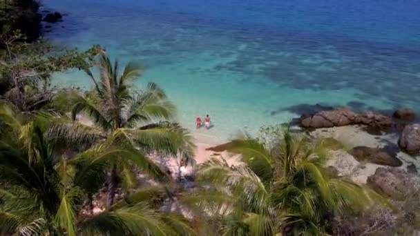 una joven pareja de hombres y mujeres en una isla tropical en Tailandia, hombres y mujeres caminando en una playa con palmeras y turqouse océano de color en Koh Wai Island Trat Tailandia  - Imágenes, Vídeo