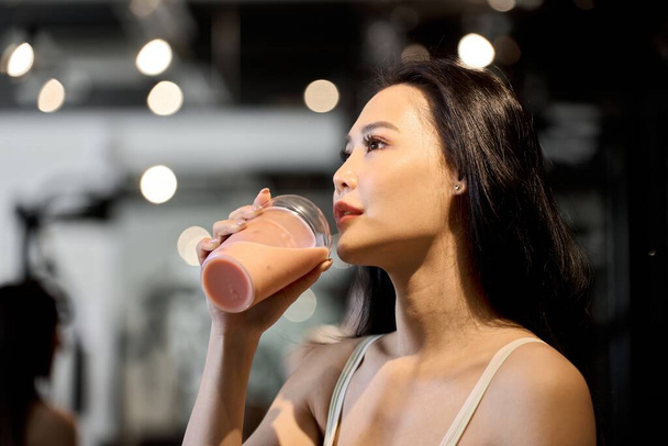 Female trainee drinking protein at the gym - Photo, Image