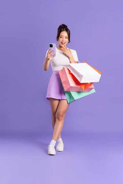 Junge Asiatin mit Einkaufstasche auf lila Hintergrund - Foto, Bild