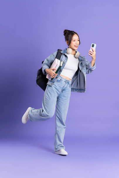 Retrato de uma bela estudante asiática usando uma mochila em um fundo roxo - Foto, Imagem