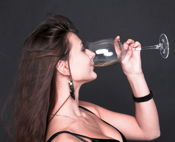 Portrait of beautiful brunette girl drinking champagne from wine - Photo, Image