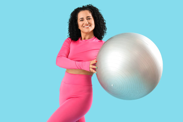 Donna adulta sportiva con fitball su sfondo blu - Foto, immagini