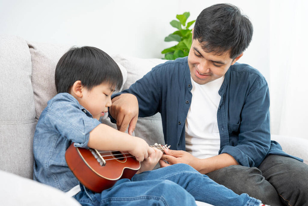 Onnellinen yksinhuoltajaisä soittamassa musiikkia pikkupojan kanssa. Hauska perhe on onnellinen ja innoissaan talossa. Isä ja poika pitävät hauskaa yhdessä. Ajankohta, loma - Valokuva, kuva