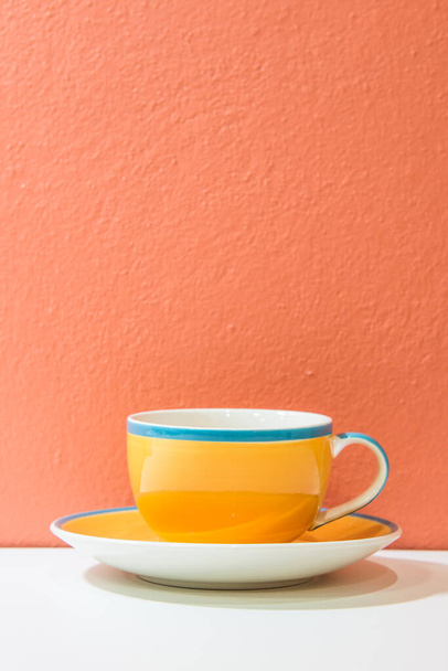 Желтая чашка кофе с оранжевой стеной и белым полом, Таиланд. - Фото, изображение