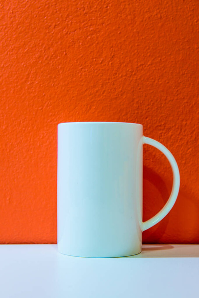 White ceramic cup with orange wall and white floor, Thailand. - Photo, Image
