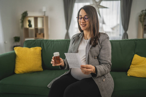 pregnant woman hold pills and prescription Expectant mother read leaflet before take a tablets medication or supplement - Photo, Image