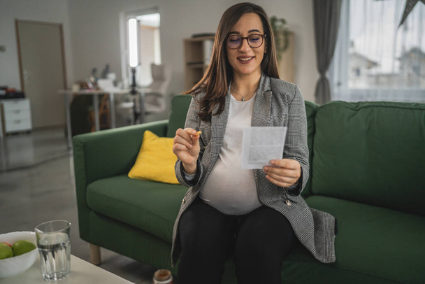 беременная женщина держать таблетки и рецепт беременной матери читать листовки, прежде чем принимать таблетки лекарства или дополнения - Фото, изображение