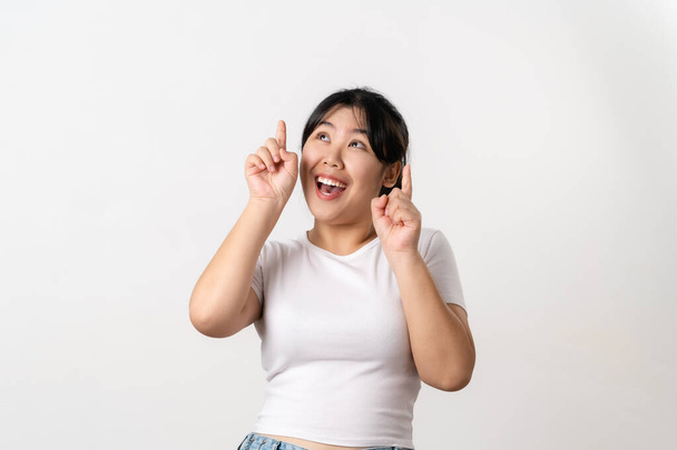 De vrolijke jonge Aziatische vrouw heeft grote gedachte, het vinden van inspiratie of oplossingen om een probleem op te lossen. wijsvinger omhoog staande op witte achtergrond. - Foto, afbeelding