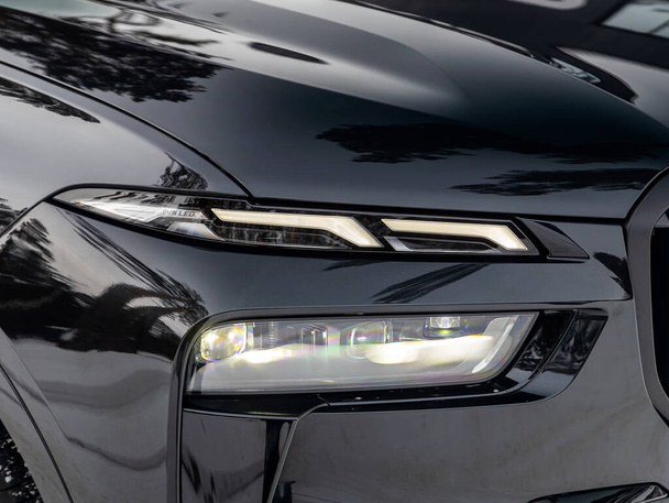 ロシアノボシビルスク - 1月 05 , 2024: ブラックBMW X7 ,近代的なラグジュアリーカーのヘッドライト. 光から輝く光沢のある光沢のある光沢のある光沢のあるガラス車のヘッドライト - 写真・画像