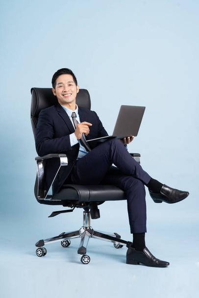 Aasialainen liikemies mies muotokuva istuu tuolilla ja eristetty sinisellä taustalla - Valokuva, kuva