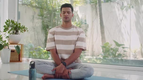 Mediana larga oportunidad de deportista relajado practicando la posición de loto mientras hace yoga en el suelo en casa - Imágenes, Vídeo