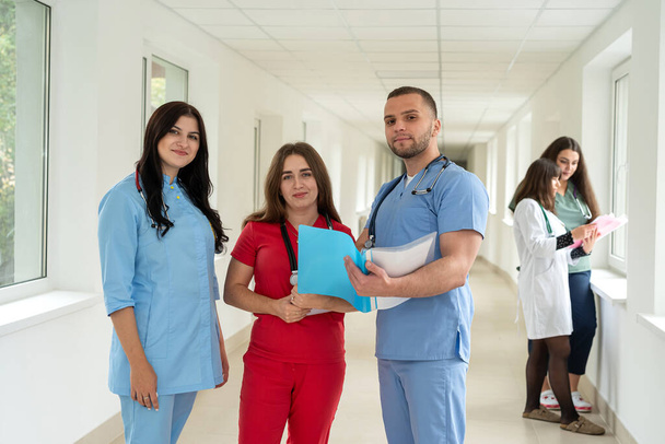 Kaukasische Medizinstudenten tragen Uniform im Flur einer modernen Klinik. Ärzteporträt im Gesundheitswesen - Foto, Bild