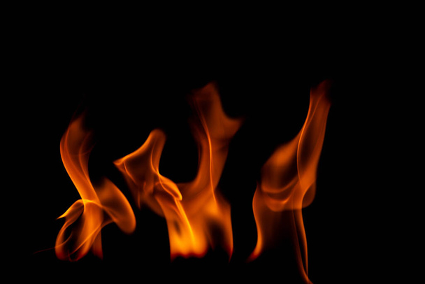 Heiße Flammen auf schwarzem Hintergrund. Schöne Feuerflamme im Dunkeln. Abstrakt von brennenden Flammen und Rauch. - Foto, Bild