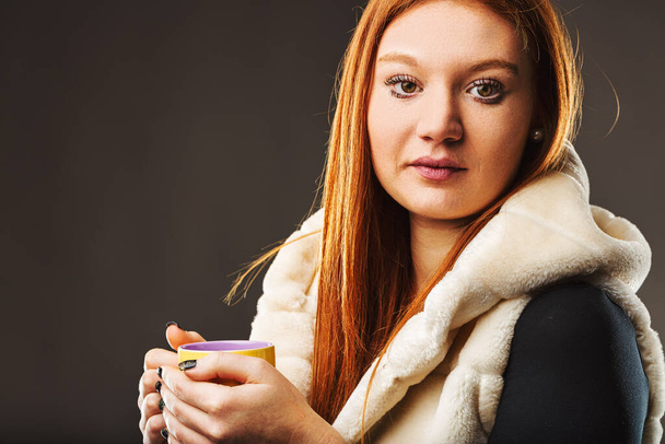 Femme trouve réconfort dans une boisson chaude, sa tenue suggérant une pause du froid à l'extérieur - Photo, image