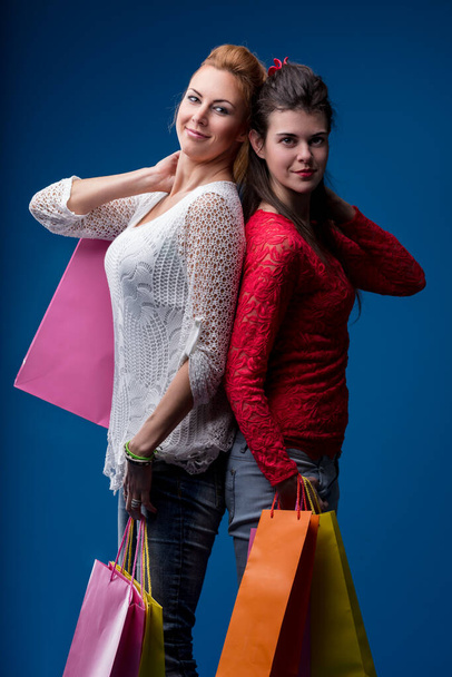 Back-to-back shoppers exude cheer, their shopping success displayed in vivid bags - Photo, Image