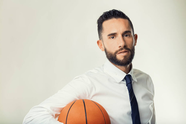 Мужчина в деловой одежде представляет баскетбол, метафору стратегического планирования и исполнения - Фото, изображение