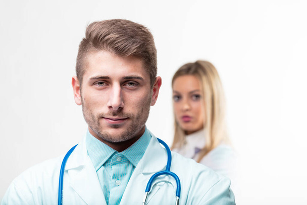 Jonge medische professional in scherp detail met een vrouwelijke vennoot in zachte focus, die diepte op de werkplek aangeeft - Foto, afbeelding