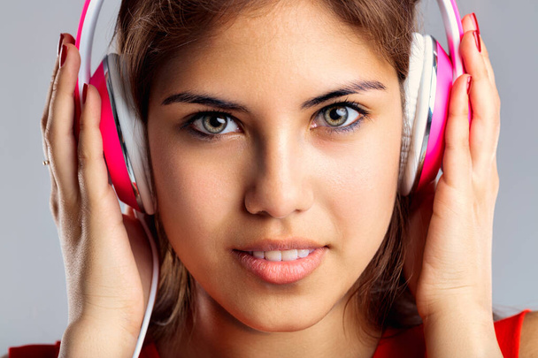 Music enthusiast's experience is accentuated by her bright headphones and attentive gaze - Photo, Image