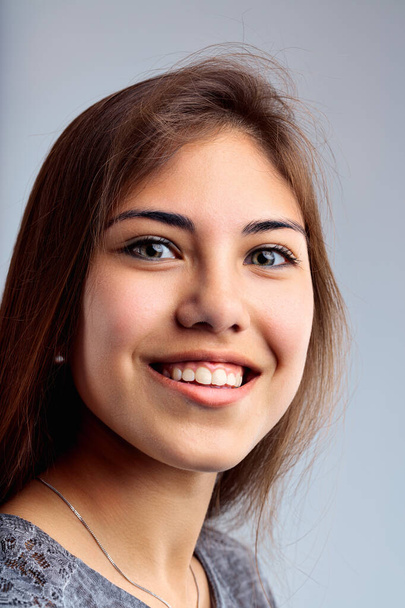 Portret uwiecznia młodą kobietę z wciągającym uśmiechem, brązowymi oczami i swobodnym ubraniem - Zdjęcie, obraz