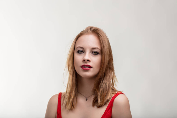 Neutral background highlights the woman's red clothing and thoughtful expression - Photo, Image