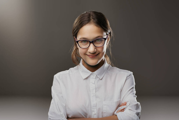 Νεαρή γυναίκα άτακτο χαμόγελο και ακαδημαϊκά γυαλιά προτείνουν μια παιχνιδιάρικη διάνοια, έτοιμη για ακαδημαϊκές προκλήσεις - Φωτογραφία, εικόνα
