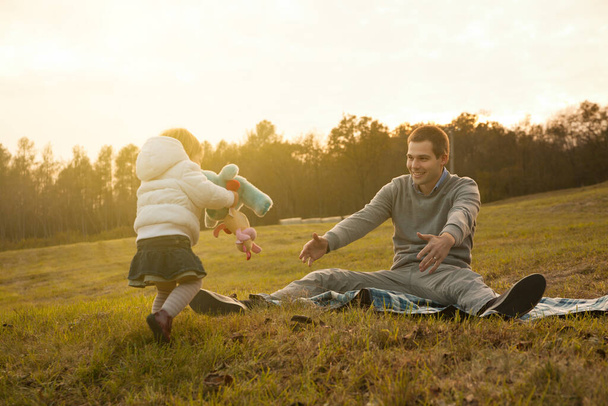 La risa al aire libre llena el aire cuando un niño se acerca a su padre que espera, el vínculo entre ellos inconfundible - Foto, Imagen